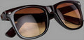 Black-framed sunglasses with brown lenses on a gray background
