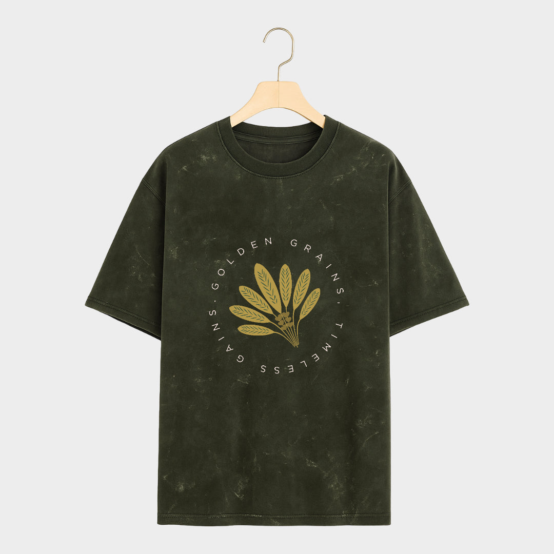 Green t-shirt with gold leaf design and text on a gray background