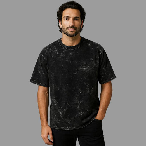 Man wearing a black distressed t-shirt against a gray background