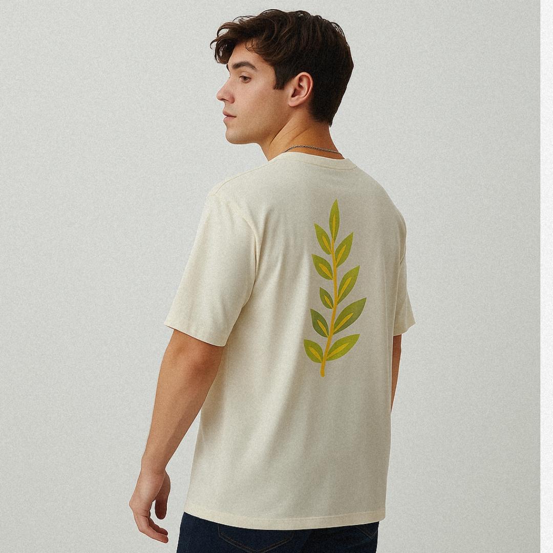 Person wearing a beige t-shirt with a green leaf design on the back against a plain background
